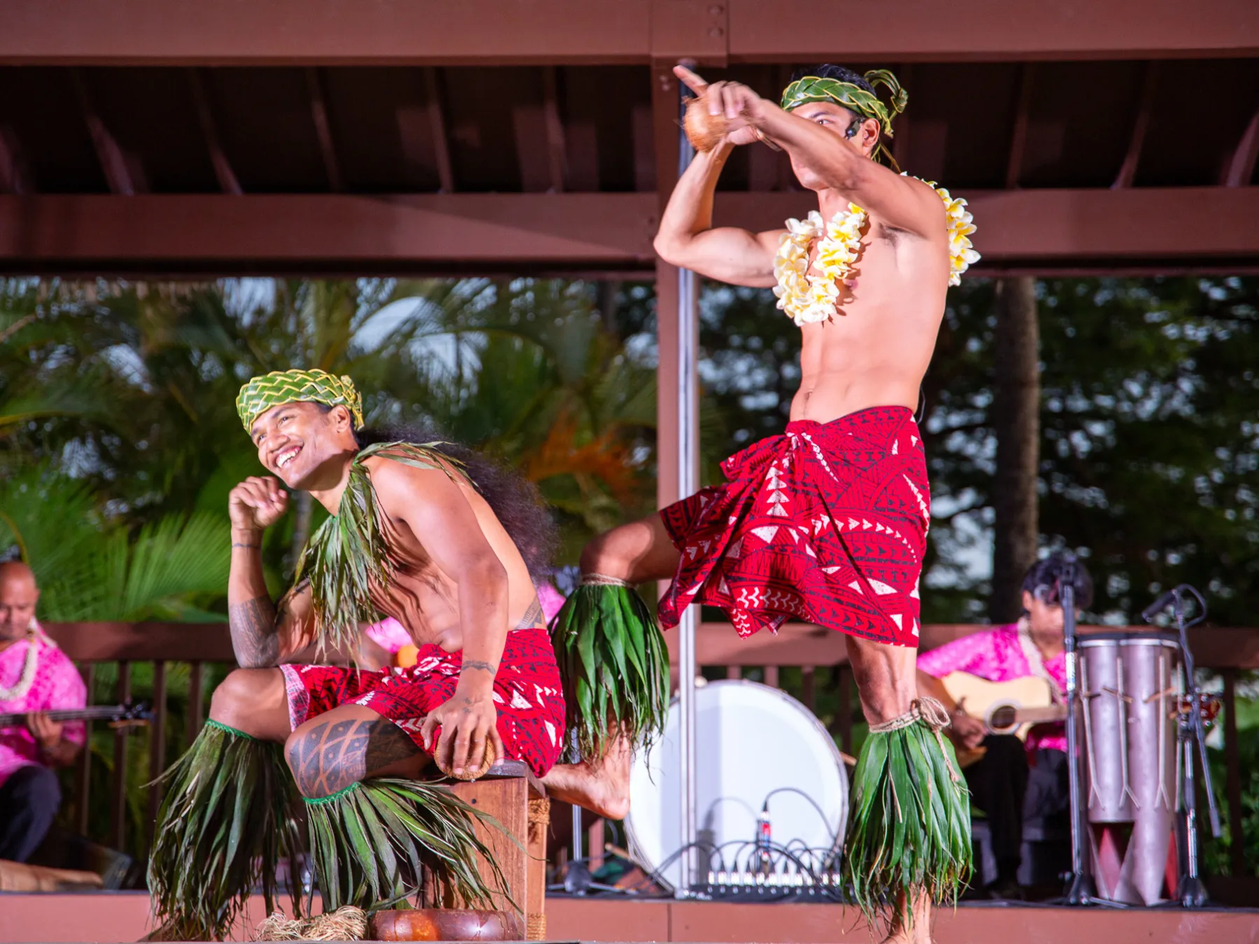 a group of people sitting at a table with a vase of pink flowers